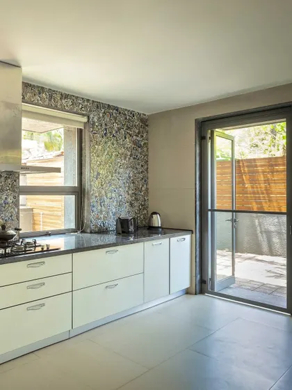 A kitchen with a unique, textured backsplash that opens up to an outdoor area, blending indoor functionality with access to fresh air.