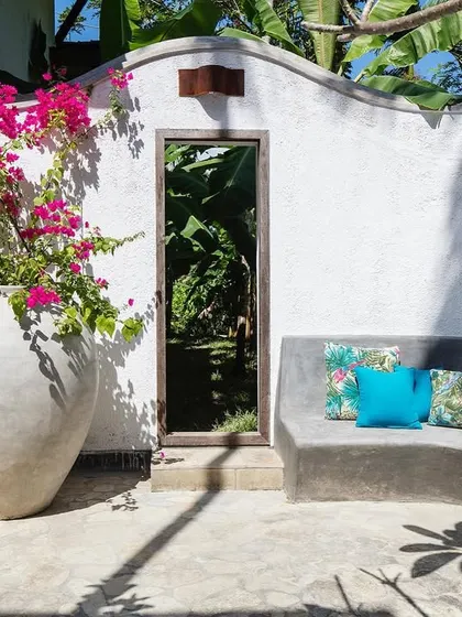 A built-in seating area in the main courtyard at Jalakara, brightened by bougainvillea and vibrant blue cushions.