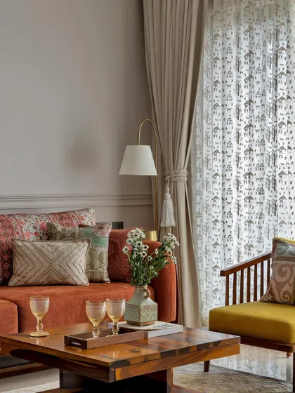 This living room balances simplicity and vibrancy. The earthy terracotta sofa, adorned with patterned cushions, is contrasted by a bright yellow accent chair, creating a space that is both warm and cheerful.
