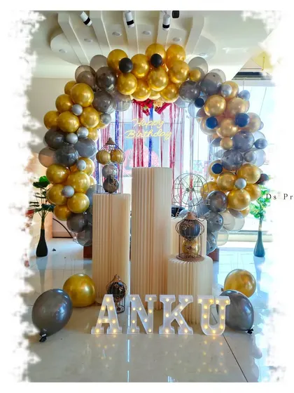 For a sleek and stylish adult birthday party, I used a gold, black, and silver color scheme. This setup features a balloon arch, fluted plinths for the cake, and light-up marquee letters for the name.