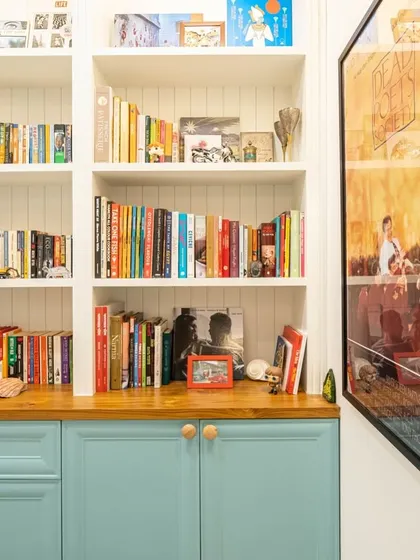 A serene study room created by renovating a washroom, featuring aqua blue cabinets, a raw wood log tabletop, and ample bookshelves.