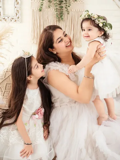 A mother and her two daughters, sharing a beautiful moment in matching white dresses.