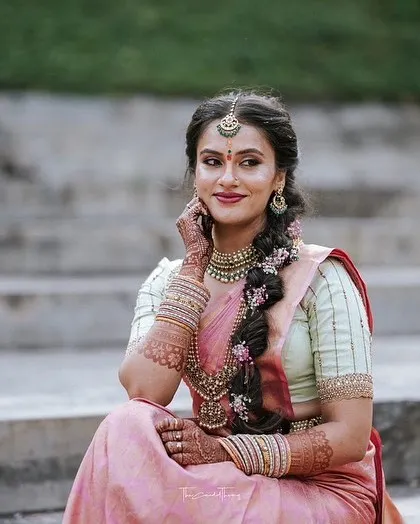 A candid shot of the bride in her pastel pink saree, capturing a natural and thoughtful moment.