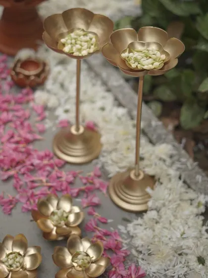 Elegant brass lotus-shaped candle or flower holders. These small, beautiful details are scattered around the event space, adding a touch of metallic shine and traditional symbolism.