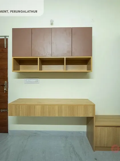 A minimalist floating study unit in our Perungalathur project, featuring a light wood desk and overhead cabinets, perfect for a compact space.