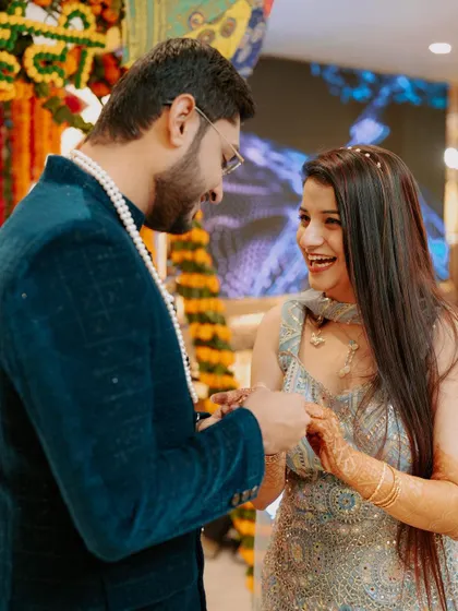 A playful and intimate moment during the ring exchange at a Mehendi or Sagan ceremony. The laughter between the couple is infectious.