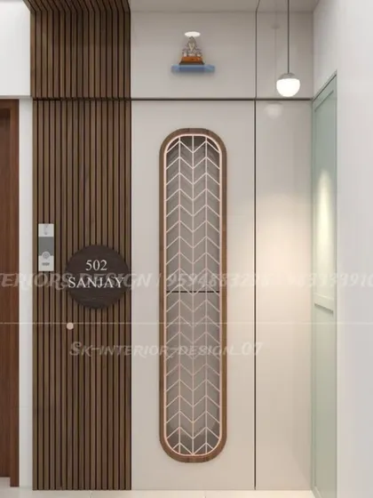 A clean and modern entrance design. The main door features a vertical jali panel, and the adjacent wall has wood fluting and a simple nameplate.