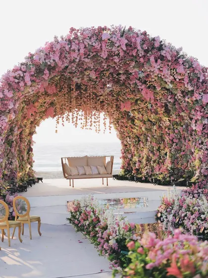 We designed this colossal floral mandap to feel like a natural wonder. The structure, completely covered in thousands of pink and lavender flowers, creates an immersive sanctuary for the wedding ceremony, with the ocean as the backdrop.