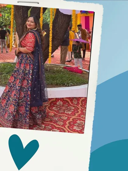 A happy client at an outdoor event in a navy and red floral lehenga. The print is bold and beautiful, great for making a statement.