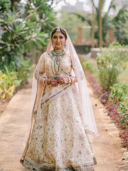 A full-length shot of the bride in her beautiful beige and pastel lehenga. The look is modern yet traditional, perfect for a daytime wedding.