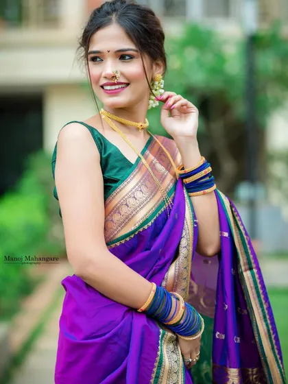 A beautiful photo of a model in a purple and green Paithani, smiling brightly.