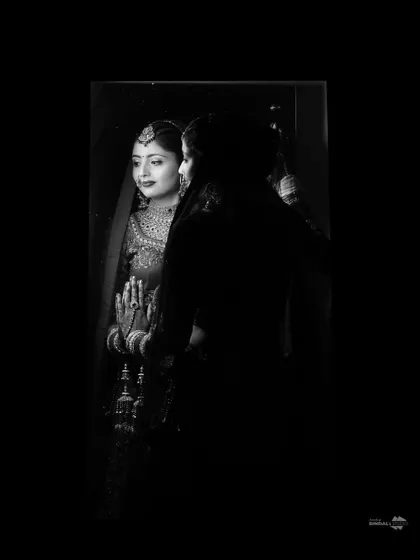 A beautiful black and white portrait of the bride looking into a mirror. The play of light and shadow creates a timeless and contemplative mood.