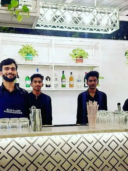 A modern and stylish bar with a white and black geometric pattern. Set up for a wedding, this bar adds a contemporary touch, complemented by the fresh greenery and a clearly displayed cocktail menu.