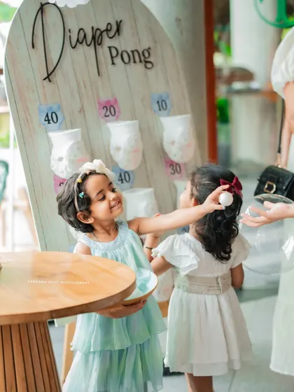 A candid moment of two little girls playing 'Diaper Pong' at a baby shower. This photo perfectly captures the fun and games of the celebration in a natural, unposed way.