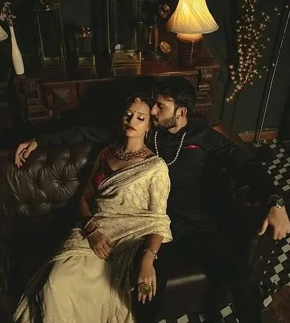 A tender moment captured in a vintage-style setting, with the groom-to-be kissing his partner's forehead.