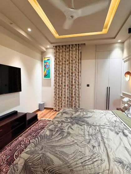 This angle showcases the full layout of the bedroom, including the media console and the warm, indirect lighting from the false ceiling, which creates a relaxing ambiance.