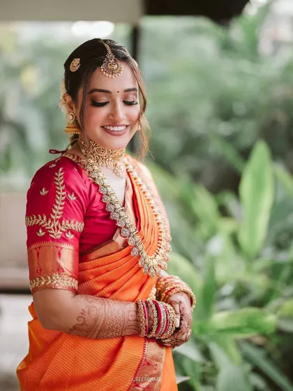 A smiling bride is the most beautiful bride. This close-up captures her joy and the flawless, balanced makeup that enhances her natural beauty without looking heavy. The orange and pink saree is a classic combination.