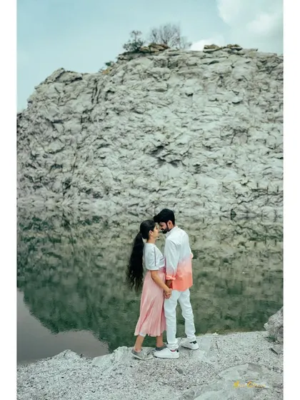 A couple stands together on a rock, framed by the immense quarry wall and its reflection in the water. A powerful and artistic composition.