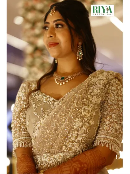 A closer look at the intricate workmanship on Greeshma's reception blouse. The sheer fabric is adorned with a dense pattern of pearls, sequins, and delicate threadwork, creating a rich texture that is both subtle and striking.