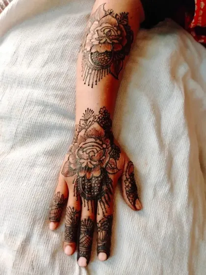 A bold and beautiful rose design. This style uses shading to create depth, making the flowers pop. The pattern extends up the arm with a matching floral motif.