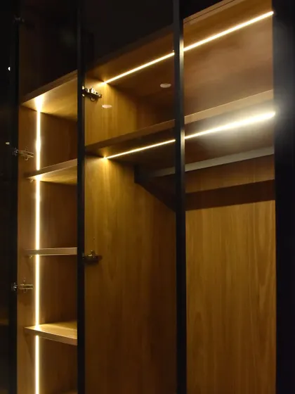 Here you can see the combination of shelf and rod lighting within a single wardrobe unit. We use high-quality German hardware for the soft-close hinges on the glass doors.