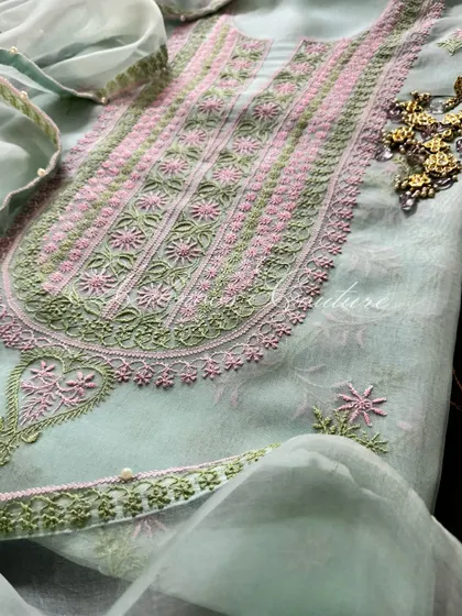 A close-up of the neckline, styled with traditional earrings, showing the intricate floral embroidery.
