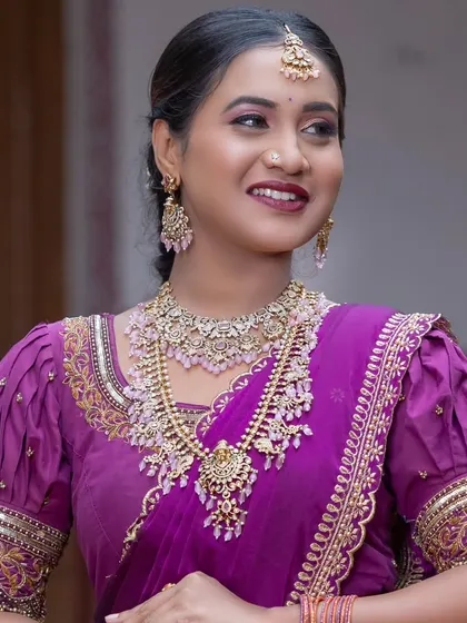 This bride has paired her purple saree with a lovely Victorian-style necklace set with pink beads.