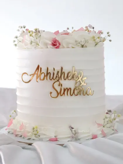 This minimal white cake with a custom name topper is perfect for an intimate engagement or 'baat pakki' ceremony.