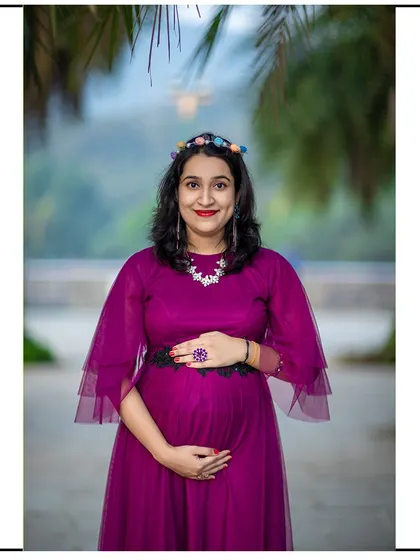 A happy and bright close-up portrait of a mom-to-be, accessorized with a colorful headband and necklace.