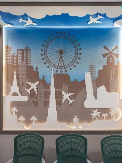 This custom-designed wall art in a conference room for a travel company features iconic global landmarks. The layered silhouette design is backlit to create depth and serves as a powerful visual anchor that reinforces the client's brand identity.