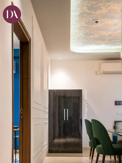 A view from the passage into the dining room, where deep green chairs and a sky-printed ceiling wallpaper create a unique and chic atmosphere. This shows our approach to designing every part of the home, including transitional spaces.