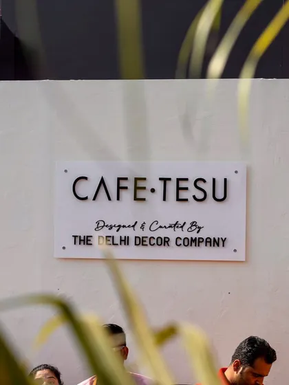 The official branding sign for the Cafe Tesu pop-up, clearly stating it was 'Designed & Curated By The Delhi Decor Company'.