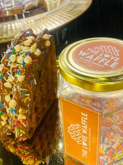 A waffle with chocolate, sprinkles, and white chocolate chips.