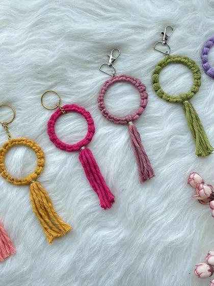 A new keychain design featuring a macrame-wrapped ring with a matching tassel. These are available with either a traditional keyring or a clasp, and come in many vibrant colors like pink, yellow, and purple.