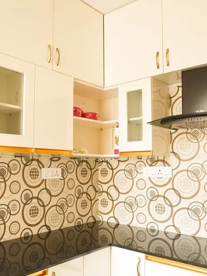 A view of the L-shaped kitchen with the distinctive patterned tile. The design includes white cabinets with glass-front doors and a black granite countertop, balancing the bold pattern with simple elements.