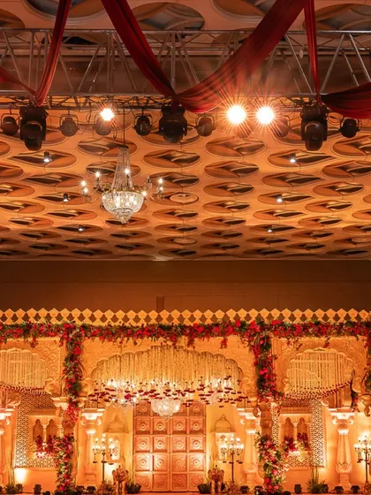 A full view of the majestic wedding stage, inspired by traditional Indian palaces. The intricate carvings, floral borders, and dramatic lighting create a truly royal setting.
