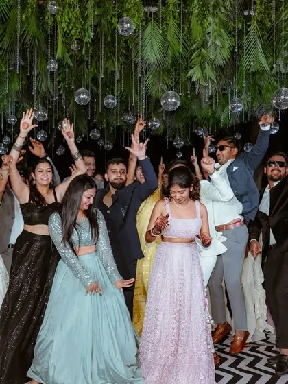 A candid shot of guests dancing under the disco balls, capturing the pure joy and energy of a well-designed sangeet night.