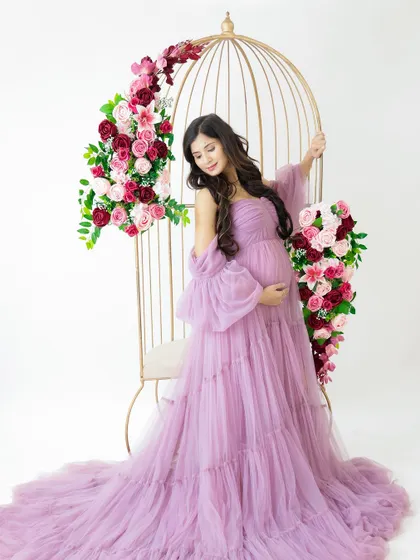A queen on her throne. This portrait features a beautiful birdcage chair prop, with the mom-to-be looking regal in a flowing lavender gown.