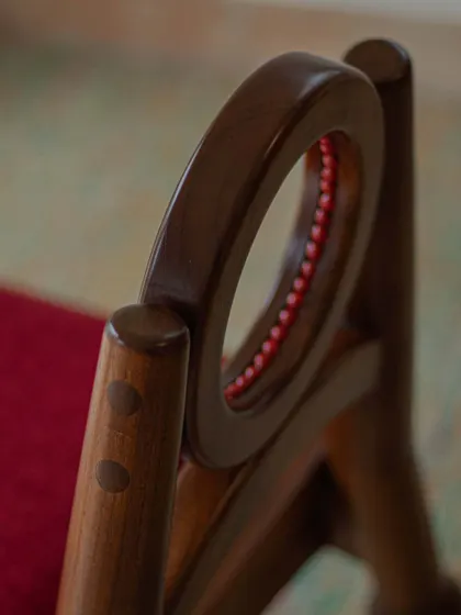 A series of images detailing the Manjadi chair, from its hand-turned legs inspired by the seed pod to the vibrant red upholstery. These shots highlight the craftsmanship and the deep cultural narrative behind this unique design.