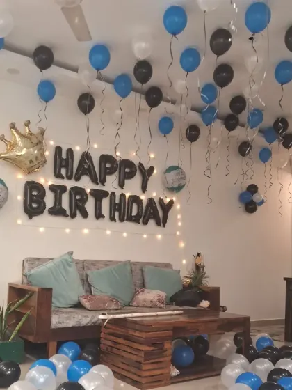 A full view of the blue, black, and white birthday room decoration. The floor and ceiling are filled with balloons, creating a festive atmosphere.