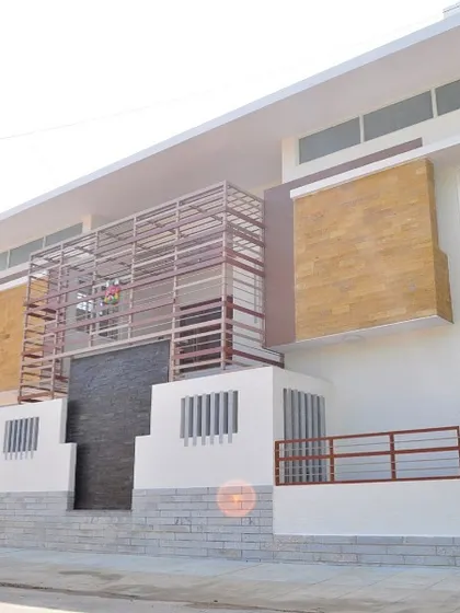 The Prabhakar Residence in Bangalore presents a modern exterior with a mix of materials, including white plaster, stone cladding, and metal screening. The design creates a layered and textured facade that is both contemporary and visually engaging.