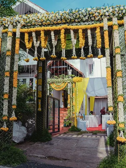 A grand floral arch at the entrance, made with lush garlands of white and yellow marigolds, creates an impressive and traditional welcome for all the guests.