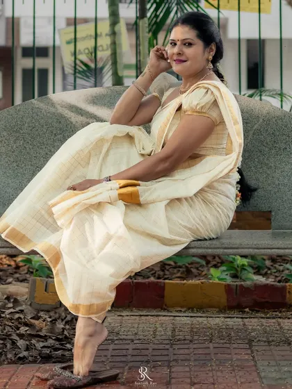 A graceful pose on a bench, showcasing the beautiful fall of the cotton Kasavu saree. The right drape is key to making a saree look elegant.