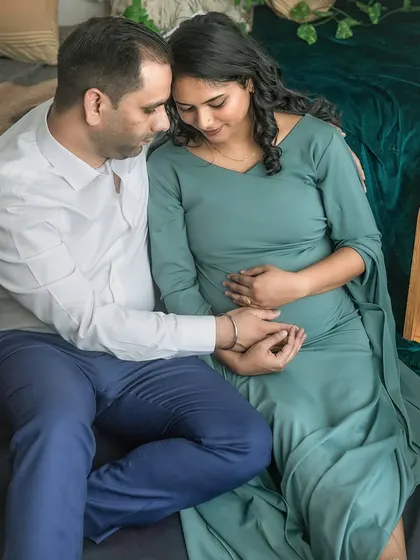 An expecting couple sits together in a quiet, intimate moment during their studio session. Their gentle hold and soft expressions convey a sense of peace and shared love.