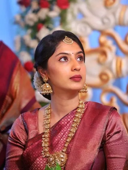 A candid shot capturing the serene elegance of this traditional look. The focus is on defined eyes, a matte mauve-brown lip, and hair pulled back neatly with jasmine flowers.
