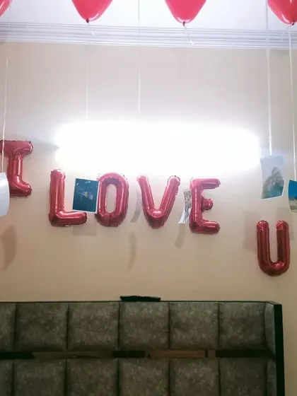 A romantic room decoration for a Valentine's gift or anniversary surprise. The "I LOVE U" foil balloons and photos hanging from heart-shaped balloons add a personal touch.