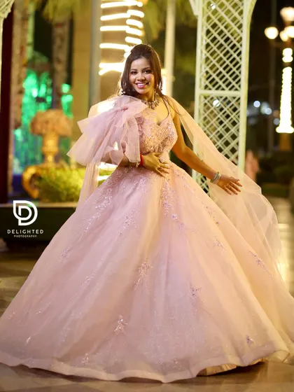 A stunning full-length portrait of the bride-to-be at her engagement, looking like a princess in a flowing pink ball gown.