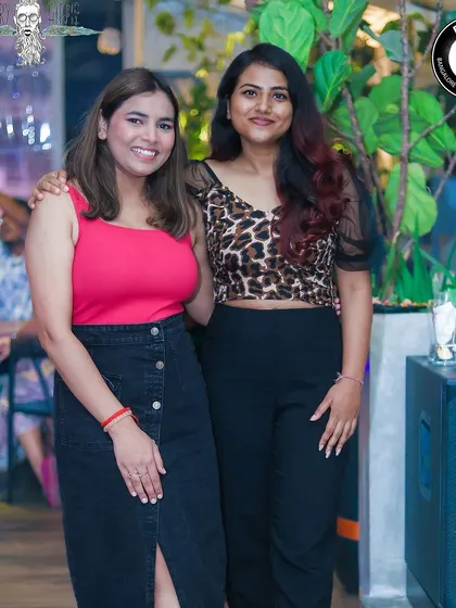 Two friends smiling and enjoying the music at the rooftop party.