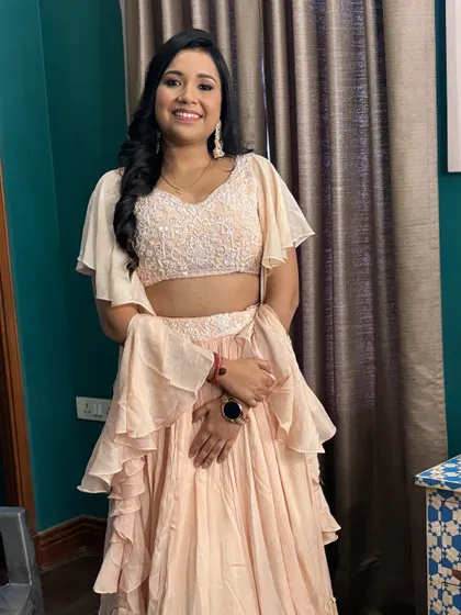 A full-length shot of the client, showcasing her beautiful ruffled lehenga and the soft, elegant makeup that completes the look.