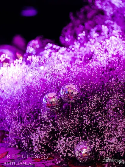 A close-up of disco balls nestled within a cloud of purple-lit baby's breath, a fun detail that perfectly captured the glamorous party vibe of the Sangeet.
